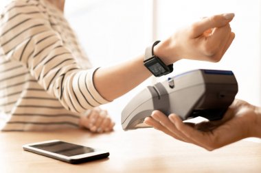 Mal veya hizmet için ödeme yaparken elektronik makine üzerinde tutarak bilek akıllı saat ile genç modern kadın Kolu
