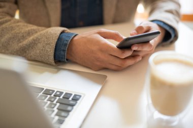 Kafede masa başında otururken, ağ yaparken ve kahve içerken akıllı telefonda kaydırma veya mesajlaşma genç mobil işadamı