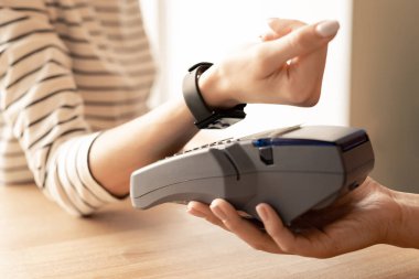 Mağaza veya kafede elektronik makine ile temassız ödeme yapmak için bilek üzerinde akıllı saat kullanarak casualwear Çağdaş kız