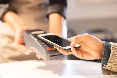 Kafe veya restoranda sipariş için ödeme yaparken akıllı telefon temassız ödeme sistemi kullanarak çağdaş işadamı