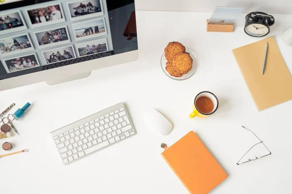 Overview of designer workplace with set of supplies, keypad, mouse, part of computer monitor and snack