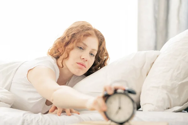 Неймовірна Молода Жінка Лежить Ліжку Розтягуючи Руку Щоб Вимкнути Будильник — стокове фото