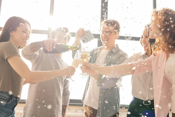 One of happy guys shooting his friends going to make toast with champagne while enjoying home party