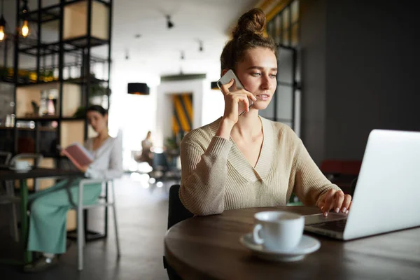 Unga Upptagen Kvinnlig Anställd Casualwear Pratar Med Smartphone Medan Surfar — Stockfoto