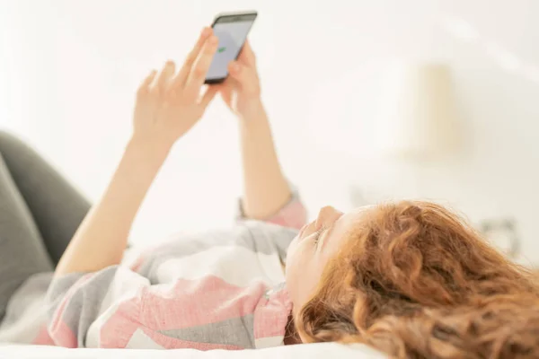 Genç Kadın Genç Kız Yatakta Uzanıyor Kaydırırken Mesajlaşırken Akıllı Telefonun — Stok fotoğraf