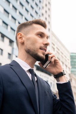 Sabah işe taşınırken akıllı telefondaki müşteri veya ortakla konuşan kendine güvenen genç işadamı
