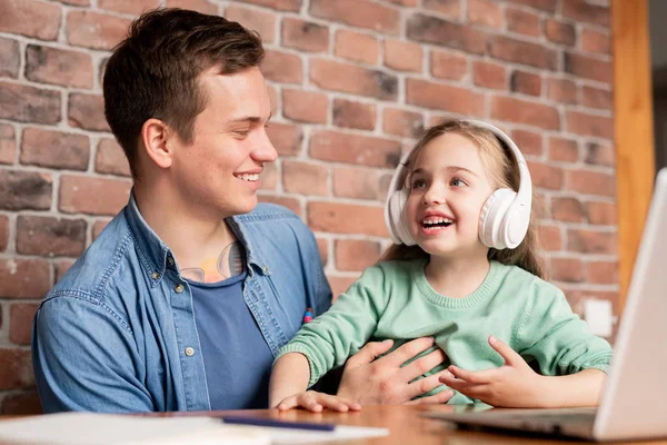 Fröhlich Aufgeregte Tochter Drahtlosen Kopfhörern Sitzt Mit Vater Tisch Und — Stockfoto