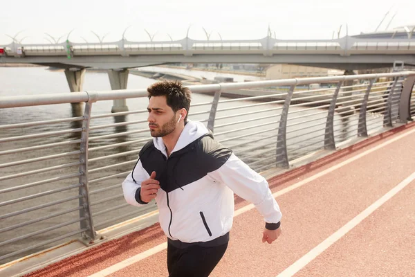 Ung Aktiv Sportsman Med Airpods Kör Längs Bridge Border Ner — Stockfoto