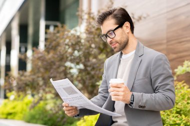 Kahve ve gazete ile genç iyi giyimli girişimci kentsel ortamda sabah harcama