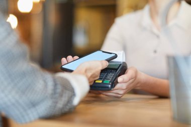 İçecek veya yiyecek için ödeme yapmak için mobil uygulamayı kullanırken elektronik ödeme makinesi üzerinden akıllı telefon tutan kafe veya restoran müşterisi