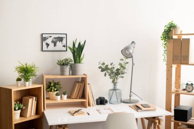 Malzemeleri ile masa ile Ofis işyeri, kitap ve saksı ve duvarda harita resmi ile ahşap raflar