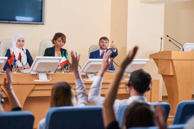 Genç kendinden emin delegelerden biri iş konferansında yaptığı konuşmadan sonra izleyiciyi soru için işaret ediyor