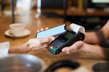 Elektronik cihaz üzerinden akıllı telefon tutarken temas olmadan ödeme mobil sistemi kullanarak çağdaş kadın