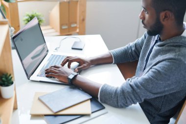 Proje için yeni fikirler bulmak için net sörf yaparken dizüstü ekran bakarak casualwear Yaratıcı genç erkek tasarımcı