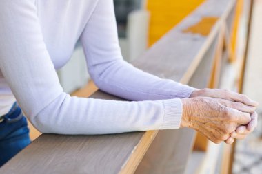 Yaz günü kır evinin ahşap korkulukları tarafından ayakta casualwear çağdaş üst düzey kadının Kolları
