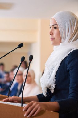 Yabancı ortaklar veya iş arkadaşları için konuşma yaparken tribün tarafından ayakta hijab genç oldukça emin Müslüman kadın delege