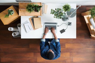 Dizüstü bilgisayar önünde iş projesi sırasında masa başında oturan kot ceketli genç işadamına genel bakış