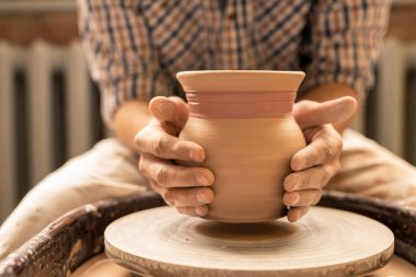 Çömlekçilik ustası veya yeni toprak eşya koleksiyonu üzerinde çalışırken tekerlek üzerinde yeni kil pot tutan genç esnaf