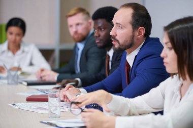 Diğer profesyoneller arasında iş semineri veya konferansta iş arkadaşı yla konuşan genç kendinden emin brokerlerden biri