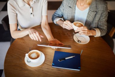 Kadın girişimcilerden biri, iş arkadaşına veya iş ortağına ortak girişim noktalarını açıklarken tabletin sergilenmesini işaret ediyor