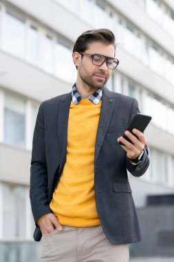 Akıllı gündelik genç işadamı elindeki akıllı telefonun ekranına bakarken iletişim iararken
