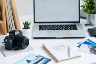 Fotokopi defteri, dizüstü bilgisayar, bazı fotoğraflar, notlar ve yaratıcı tasarımcı veya fotoğrafçı nın işyerinde kalem ile dizüstü bilgisayar