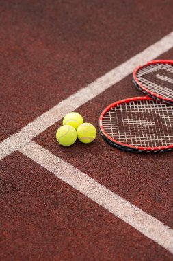 Üç sarı topa yakın beyaz çizgi ile yatan iki tenis raketleri