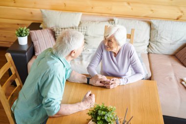 Olgun beyaz saçlı kadın o masa başında konuşma sırasında ne söylediğini dinlerken kocasına bakıyor