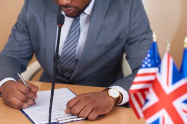 Genç Afrikalı-Amerikalı zarif delege masaya okurken ve konuşmasını hazırlarken kağıda işaret yapıyor