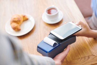 Mobil ödeme sistemi üzerinden ödeme yaparken masada oturan ve akıllı telefon kullanan restoran misafirlerinin yakın çekim
