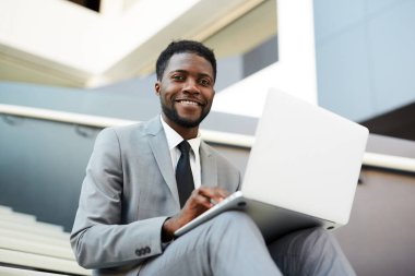 Online bilgi aramak için dizüstü bilgisayar kullanırken formalwear genç başarılı analist size bakıyor