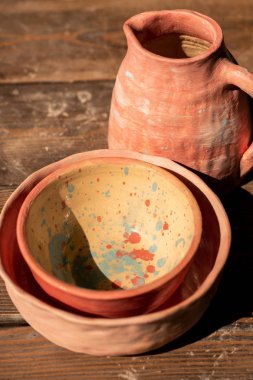 Kullanıma hazır ahşap masa üzerinde iki boyalı kase ve sürahi oluşan yeni toprak seti