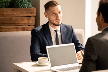 Genç kendinden emin başvuru sahibi, işverene bakıyor ve kafedeki mülakat sırasında yaptığı açıklamayı dinliyor.