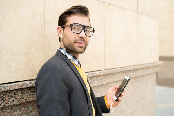 Młody Pewny Siebie Biznesmen Okularach Inteligentne Casualwear Słuchawki Słuchając Muzyki — Zdjęcie stockowe