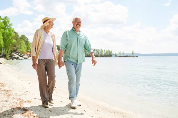 快乐和深情的老年配偶沿着海边沿着沙滩移动 享受一天 — 图库照片