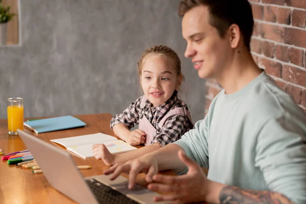彼らは一緒に創造的なホームタスクをやっている間 テーブルに座って 父親が学習アプリを示しているノートパソコンを使用して 積極的な好奇心旺盛な女の子 — ストック写真