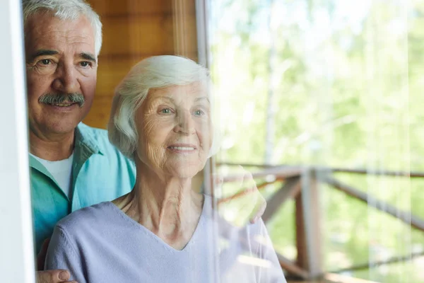 Positieve Volwassen Man Vrouw Staande Door Raam Hun Landhuis Kijken — Stockfoto