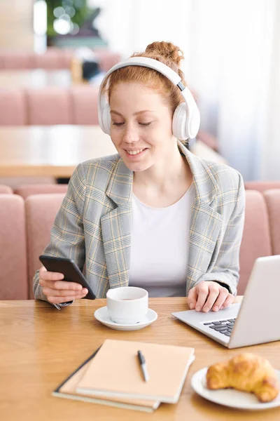 Chica Estudiante Atractiva Positiva Auriculares Inalámbricos Sentados Mesa Restaurante Moderno —  Fotos de Stock