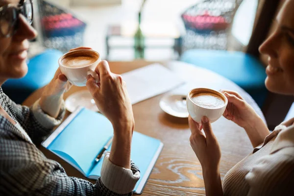 Две Успешные Бизнесвумен Чашками Капучино Сидят Столом Кафе Наслаждаются Кофе — стоковое фото