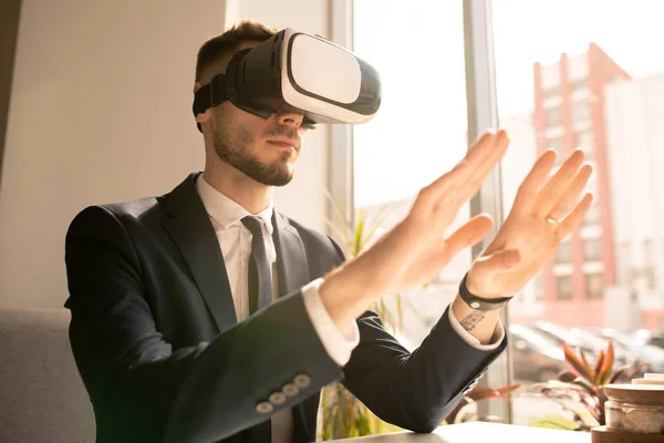 Contemporary Young Businessman Headset Touching Virtual Object Display While Sitting — Stock Photo, Image