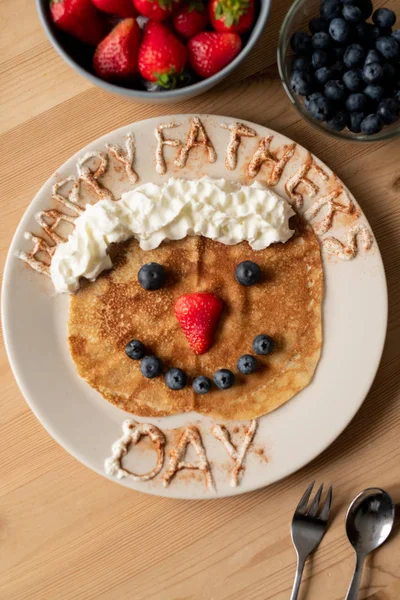 プレートにホイップクリームとベリーで飾られた面白いクレープの高角ビュー 父の日の朝食 — ストック写真