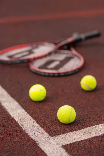 三个网球在球场上越过白线 背景有两个球拍 — 图库照片