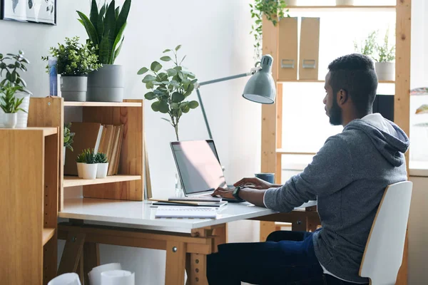 Casual Jovem Empresário Misto Olhando Para Tela Laptop Enquanto Sentado — Fotografia de Stock