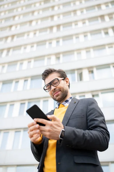在现代建筑背景中 智能男性员工在眼镜中阅读信息或在智能手机中寻找联系人 — 图库照片