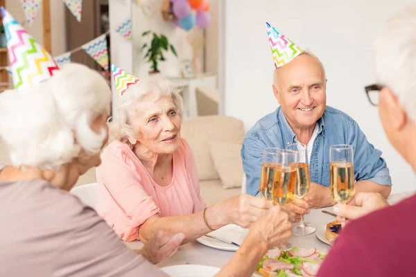 Grupa Szczęśliwych Starszych Przyjaciół Klinowanie Flety Szampana Przez Serwowany Stół — Zdjęcie stockowe
