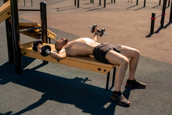 Aktivní Svalnatý Chlapík Zvonečky Dřevěné Lavici Při Cvičení Sportovní Půdě — Stock fotografie