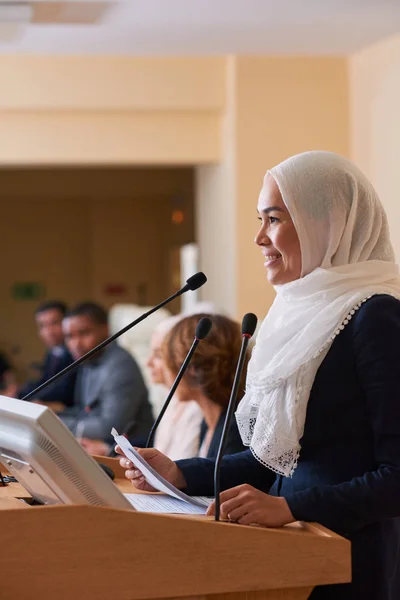 Muito Jovem Sorridente Muçulmano Orador Feminino Pelo Tribuno Fazendo Relatório — Fotografia de Stock