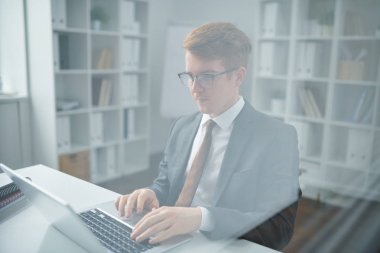 Genç kendinden emin tüccar takım elbise li dizüstü bilgisayar ekranında online veri ile bakarken analiz ederken