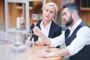 Rengini değerlendirirken bokal şarap örneğine bakarken formalgiyimde ciddi ve özenli sommeliers