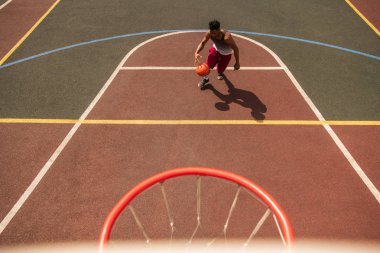 Genç profesyonel basketbolcu topu sepete atmak için giderken kort aşağı çalışan